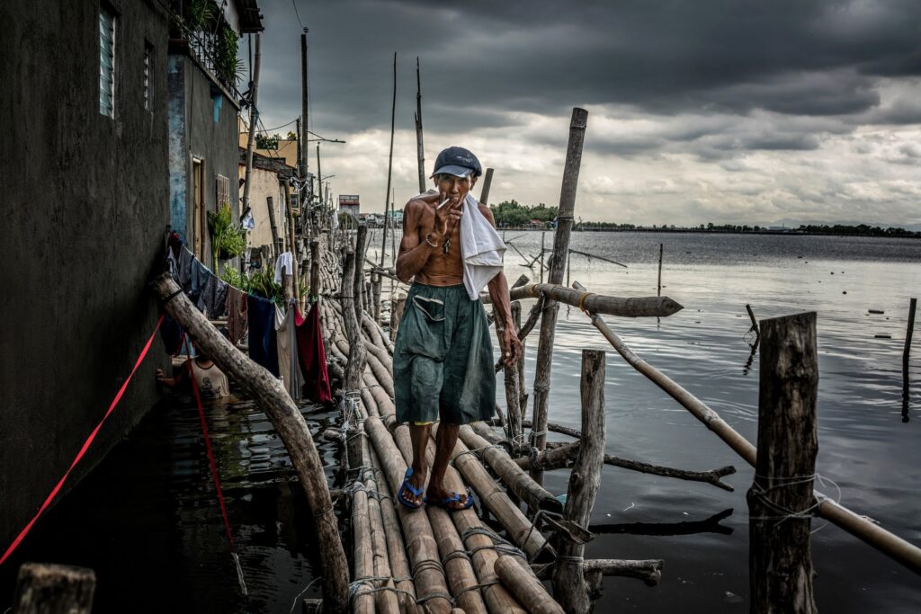 A fisherman navigates a raised bamboo walkway that remains above the high tide water mark connects two parts of Binuangan Island. Credit: James Whitlow Delano