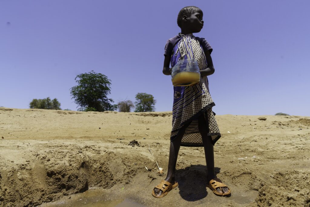 Ashan, age 5, holds a container of dirty water on the edge of Garissa, Kenya. Credit: Larry Price