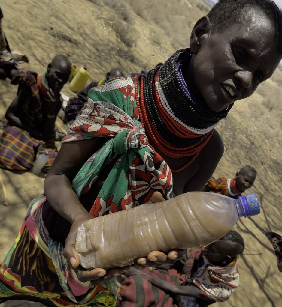 Margaret Nanok holds a plastic bottle of dirty water, dug from a sand pit in Turkana County, Kenya. Credit: Larry Price